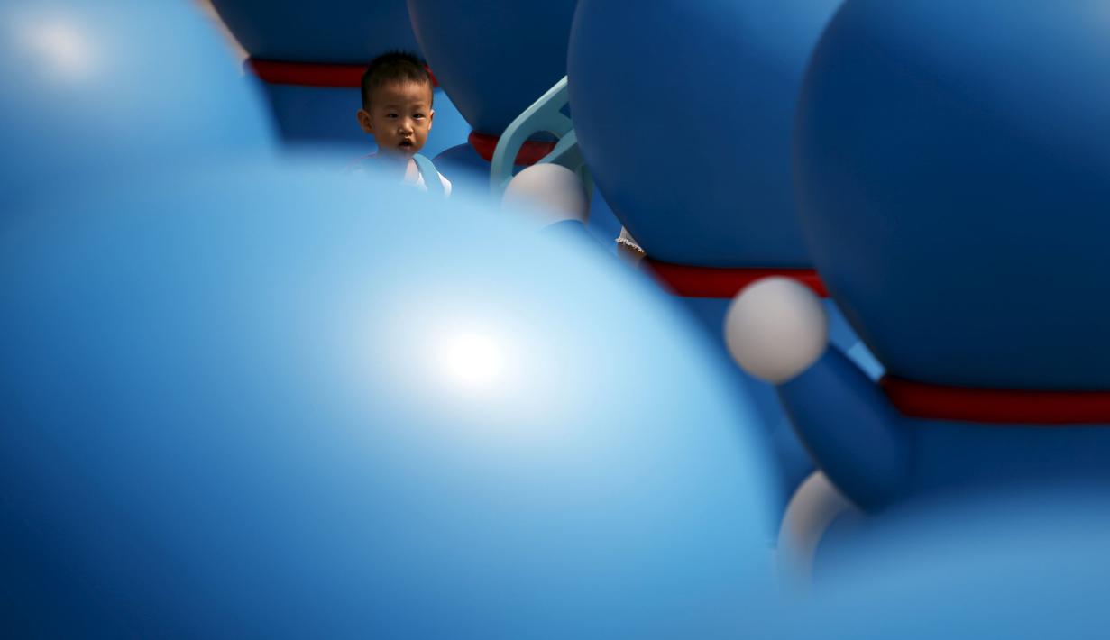 Seorang anak kecil saat bermain di antara patung – patung Doraemon, Seoul, Korea Selatan,Senin (31/8/2015). Pameran ini berlangsung dari 28 Agustus sampai 4 oktober. (REUTERS/Kim Hong – Ji)