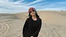 Kunjungi padang pasir di Qatar, istri Pratama Arhan, Azizah tampil kece dengan dress hitam dan sorban di kepalanya.