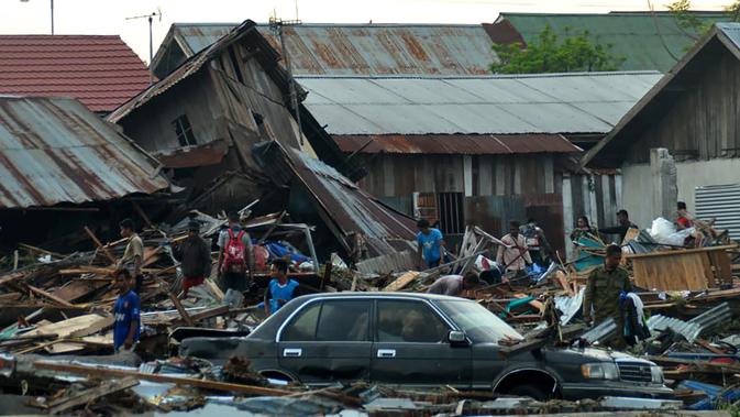 Warga mencari barang-barang yang tertimbun puing rumah mereka yang roboh akibat gempa dan tsunami di Palu, Sulawesi Tengah, Sabtu (29/9). Dampak dari bencana itu menyebabkan sejumlah bangunan hancur dan ratusan jiwa meninggal dunia. (AFP/MUHAMMAD RIFKI)