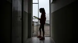 Carola Pessina bersiap bermain tenis dengan Vittoria Oliveri di atap rumah mereka selama lockdown COVID-19 di Finale Ligure, Wilayah Liguria, Italia (19/4/2020). Setiap hari Carola, 11, dan Vittoria, 13, bermain tenis dari satu atap ke atap lain di rumah mereka untuk berlatih. (AFP/Marco Bertorello)
