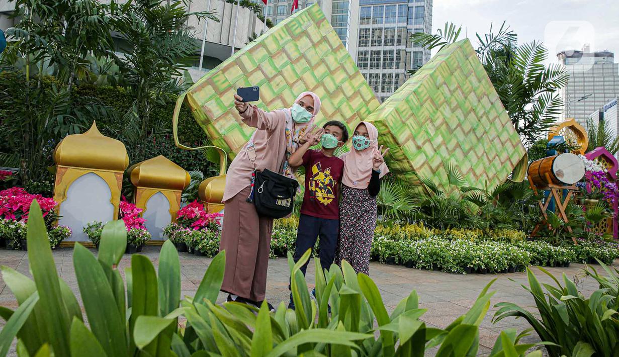 <p>Sejumlah warga berfoto dengan dekorasi bertemakan Idul Fitri di kawasan Bundaran HI, Jakarta, Rabu (27/4/2022). Dekorasi berbentuk masjid, ketupat, dan bedug yang dihiasi oleh tanaman tersebut dalam rangka menyambut Idul Fitri 1443 Hijriah. (Liputan6.com/Faizal Fanani)</p>