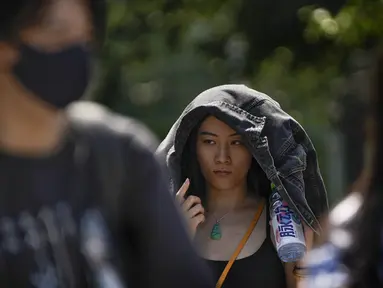 Seorang wanita menggunakan jaketnya untuk melindungi dari sinar matahari berjalan di sepanjang jalan saat ibu kota dilanda gelombang panas di Beijing, Senin, 5 Juni 2023. (AP Photo/Andy Wong)