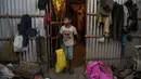 Imradul Ali (10) memegang tas kuning berisi bahan daur ulang yang dikumpulkan dari tempat pembuangan sampah, di depan kamar kontrakan keluarganya di Gauhati, India (4/2/2021).  Ali mengumpulkan beragam benda yang sekiranya dapat didaur ulang di antara tumpukkan sampah. (AP Photo/Anupam Nath)