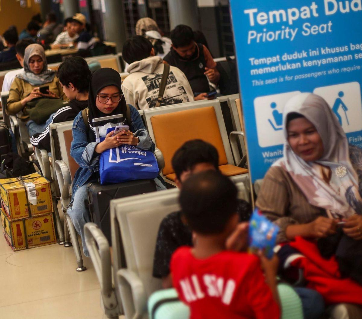 Seorang penumpang wanita menyibukkan diri dengan bermain ponsel saat menunggu keberangkatan kereta di Stasiun Pasar Senen, Jakarta, Rabu (3/4/2024). Foto:  Liputan6.com / Angga Yuniar