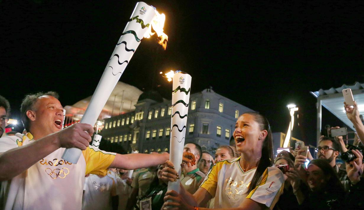 Supermodel Adriana Lima dan Sekretaris Pariwisata kota Rio De Janeiro, Antonio Pedro ketika membawa obor pada malam penyambutan Olimpiade Rio 2016 di Maua Square Rio de Janeiro, Brasil, Kamis (4/8). (REUTERS / Pilar Olivares)