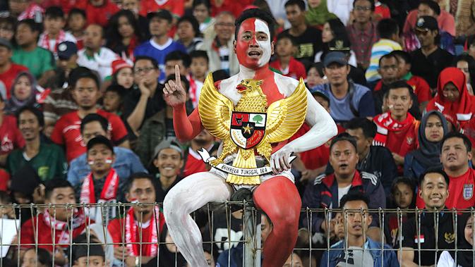 Andi Kiswantoro rela mengecat seluruh bagian tubuhnya dan memegang patung Garuda Pancasila saat mendukung Timnas Indonesia U-16. (Bola.com/Aditya Wany)