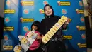 Salah satu ibu dan anak bergaya di photo booth jelang menyaksikan film Minions di Bekasi Cyber Park, Minggu (28/6/2015). Film ini bergenre animasi yang dirilis Illumination Entertaiment dan cukup diminati anak-anak. (Liputan6.com/Helmi Fithriansyah)