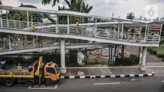 Petugas Sudin Bina Marga Jakarta Timur memperbaiki jembatan penyeberangan orang (JPO) di Jalan Otto Iskandardinata (Otista), Jatinegara, Rabu (9/2/2022). Perbaikan JPO itu tindak lanjut pasca insiden tertimpa pohon tumbang pada November tahun lalu akibat cuaca ekstrem. (merdeka.com/Iqbal S Nugroho)