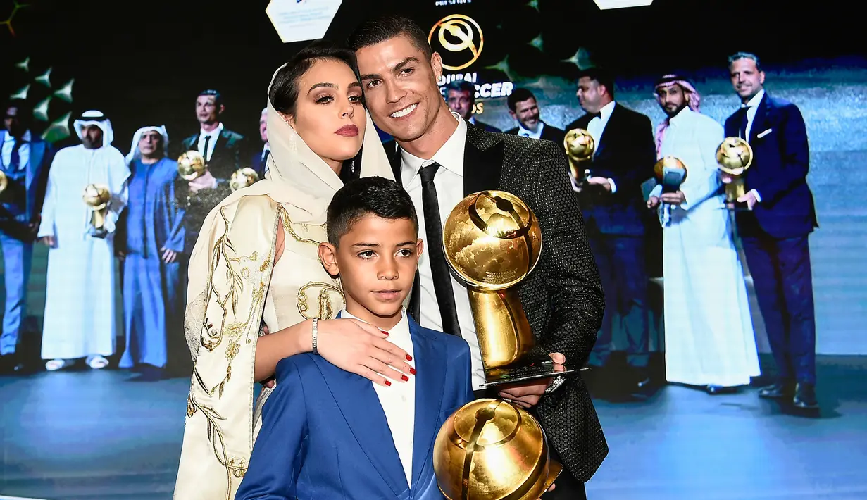 Striker Juventus, Cristiano Ronaldo bersama kekasihnya Georgina Rodriguez dan putranya Cristiano Jr berpose dengan trofi Pemain Terbaik Tahun 2018 selama Dubai Globe Soccer Awards ke-10 di Dubai (3/1). (AFP Photo/Fabio Ferrari)