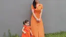 Kompak serba orange bareng Chloe, istri Jonas Rivanno ini memilih polkadot shirt dress lengan pendek dengan detail kancing di bagian depan. Sementara putrinya mengenakan sleeveless ruffle neck dress warna senada.  (Instagram/asmirandah89).