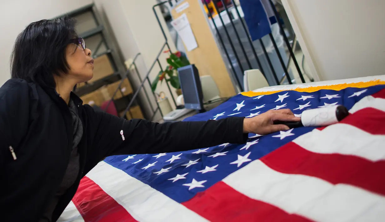 Seorang pekerja menyelesaikan pembuatan bendera Amerika Serikat yang akan digunakan untuk upacara pelantikan presiden baru Amerika Serikat Donald Trump, Alexandria Virginia, AS (10/1). (AFP/Andrew Caballero Reynolds)