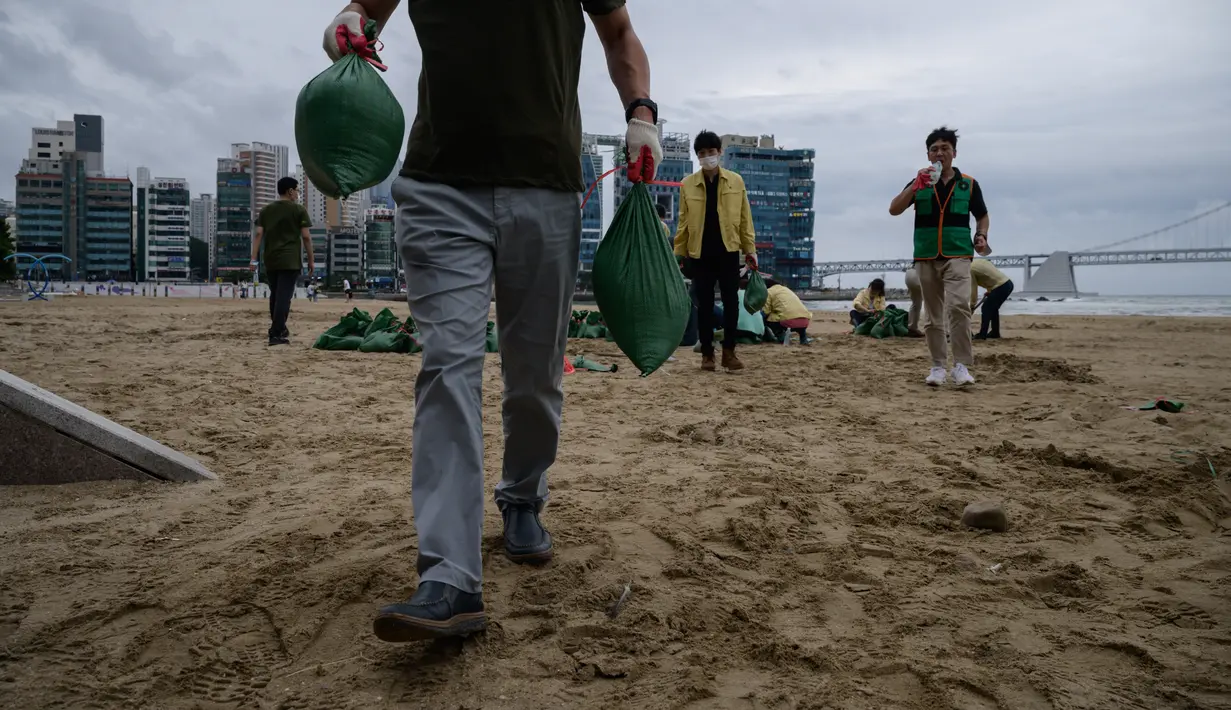 Anggota dewan distrik mengisi kantong pasir sebagai bagian dari persiapan menjelang kedatangan topan Maysak, di pantai Gwangalli di Busan (2/9/2020). Penerbangan di-grounded di Korea Selatan dan peringatan badai dikeluarkan di kedua sisi semenanjung Korea. (AFP/Ed Jones)