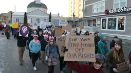 Peserta aksi dalam Women's March berjalan di jalan kawasan Washington, AS, Sabtu (21/1). Aksi ini merupakan aksi protes yang menolak Trump karena kebencian dan rasisme yang selama ini sering dilayangkannya. (AP Photo)