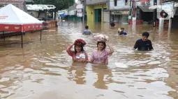 Warga melintasi banjir di perumahan Ciledug Indah, Tangerang, Rabu (1/1/2020). Banjir setinggi dada orang dewasa terjadi akibat meluapnya kali angke. (Liputan6.com/Angga Yuniar)