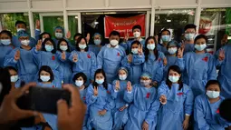 Tenaga medis mengenakan pita merah di seragamnya memberi hormat tiga jari di Rumah Sakit Umum Yangon di Yangon (3/2/2021). Petugas kesehatan di 70 rumah sakit dan departemen medis di Naypyidaw, Yangon dan kota-kota lain mengatakan, mereka tidak akan bekerja di bawah rezim militer. (STR / AFP)