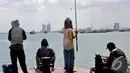 Sejumlah warga asyik memancing di kawasan Pelabuhan Muara Baru, Jakarta, Minggu (11/1/2015). (Liputan6.com/Faizal Fanani)