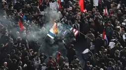 Pelayat membakar bendera Amerika Serikat dan Israel saat prosesi pemakaman Jenderal Qasem Soleimani dan sejumlah orang yang tewas dalam serangan Amerika Serikat di Teheran, Iran, Senin (6/1/2020). Pelayat meneriakkan slogan berbunyi 'Matilah Amerika' dan 'Matilah Israel'. (AP Photo/Ebrahim Noroozi)