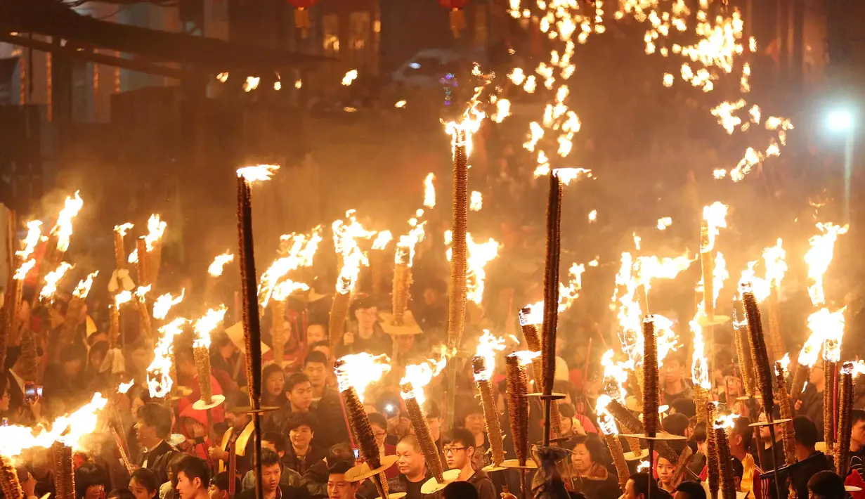 Warga berdoa sambil memegang obor saat mengikuti parade pada sebuah festival obor di Jinjiang di provinsi Fujian, China timur (24/2). Ratusan warga China mengikuti parade obor untuk keberhasilan di tahun yang baru. (AFP Photo)