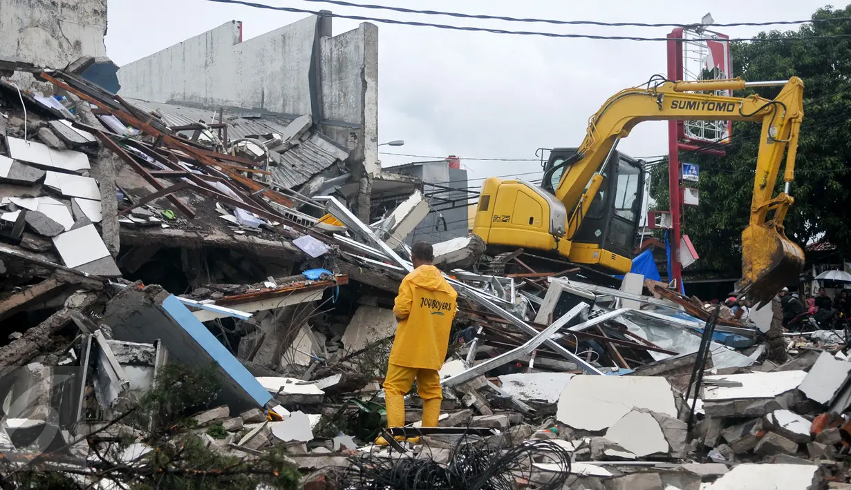 Alat berat membongkar reruntuhan bangunan PHD untuk mempermudah petugas Kepolisian melakukan proses olah TKP, Kota Bekasi, Minggu (23/10). Polisi akan melakukan olah TKP untuk memastikan penyebab ledakan tersebut. (Liputan6.com/Yoppy Renato)