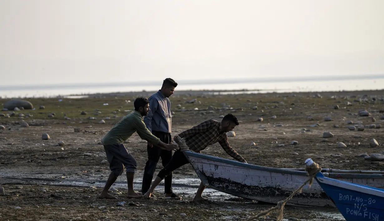 Nelayan mendorong perahu ke perairan di lahan basah Bendungan Pong di Nagrota Suriyan, sekitar 65 kilometer (40 mil) selatan Dharmsala, India, Senin (14/2/2022). Lahan Basah Pong menampung dan mendukung ratusan burung yang bermigrasi spesies di bulan-bulan musim dingin. (AP Photo/Ashwini Bhatia)