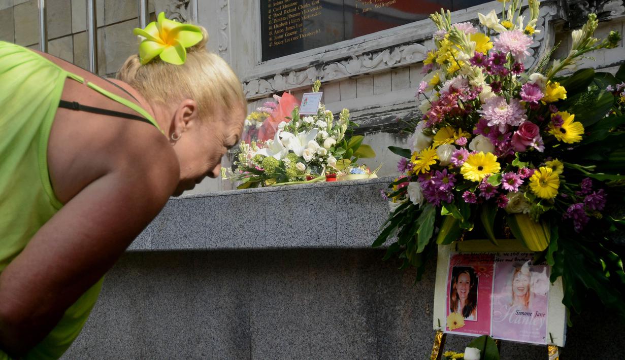 Seorang turis menunduk sambil berdoa kepada korban – korban bom bali yang terjadi 13 tahun lalu di kawasan Kuta, Bali, Senin (12/10/2015). Upacara doa dan tabur bunga dilakukan wisatawan. (AFP PHOTO/SONNY Tumbelaka)
