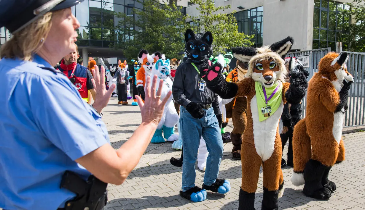 Peserta mengenakan kostum binatang berinteraksi dengan polisi saat parade konvensi Eurofurence di Berlin, Jerman (17/8). Sekitar 2700 delegasi dari berbagai negara ikut berpartisipasi dalam acara tersebut. (AFP Photo/Ganjil Andersen)