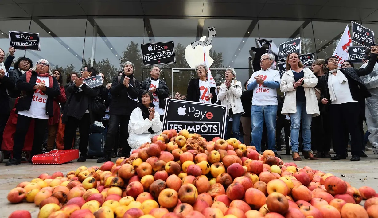 Aktivis ATTAC berada di dekat apel dan tulisan "bayar pajak anda" berunjuk rasa di luar toko Apple saat peluncuran iPhone X di Aix-en- Provence, Prancis (3/11). Unjuk rasa ini menentang penghindaran pajak oleh Apple. (AFP Photo/Anne-Christine Poujoulat)