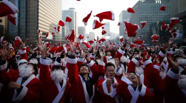 Sejumlah orang berpakaian seperti Santa Claus membuang topi mereka ke udara selama acara amal Natal di pusat kota Seoul, Korea Selatan, (24/12/2015). (REUTERS/Kim Hong-Ji)