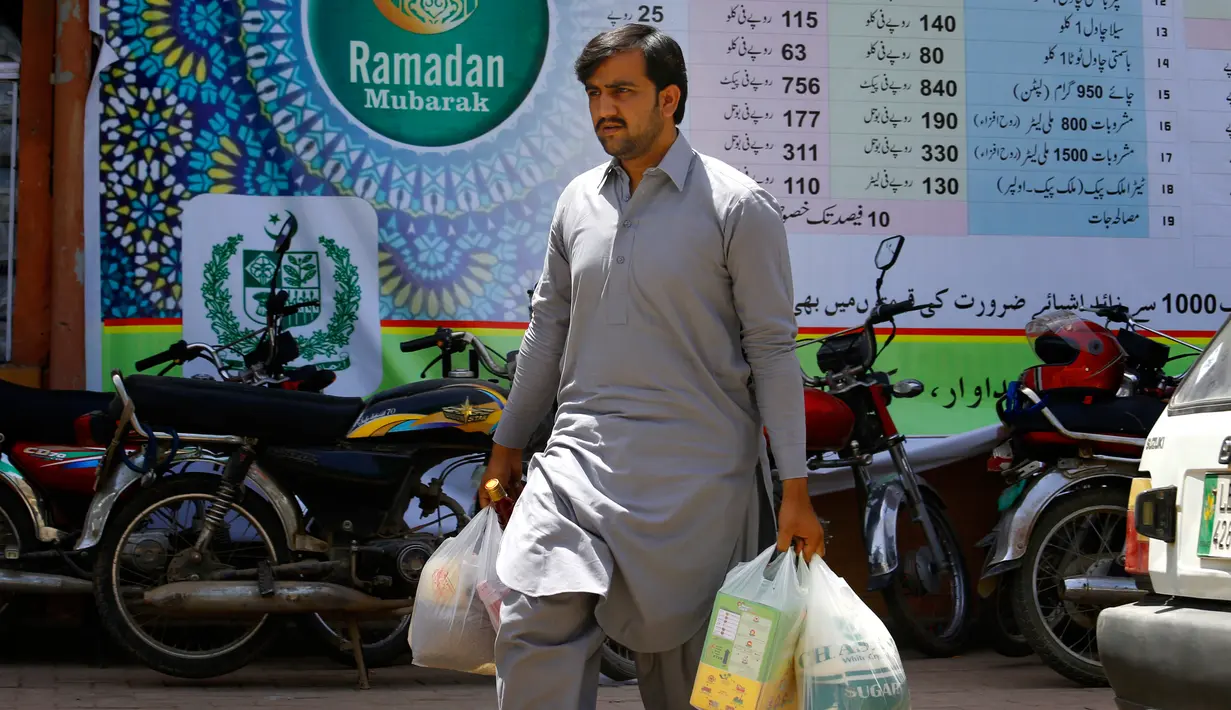Seorang pria seusai membeli stok makanan di supermarket yang dikelola pemerintah Pakistan di Islamabad, Rabu (16/5). Warga berbelanja untuk memenuhi kebutuhan menyambut Puasa Ramadan yang dimulai pada Kamis (17/5). (AP/Anjum Naveed)