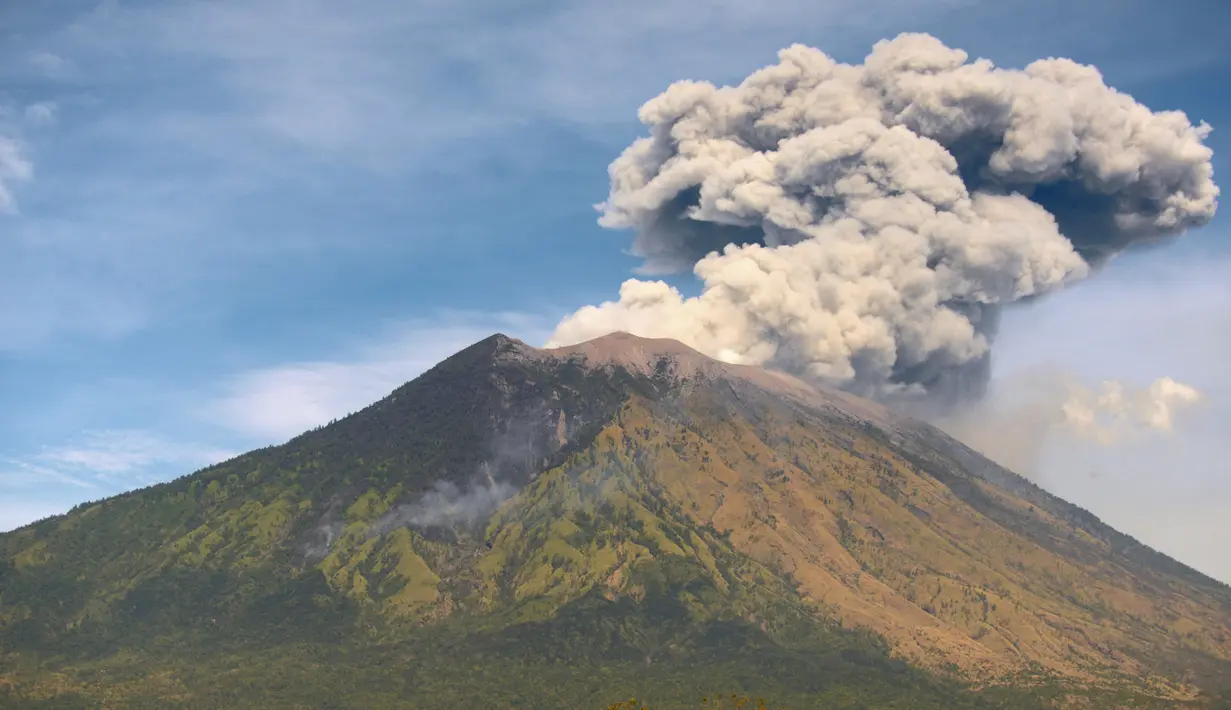Gunung Agung mengeluarkan asap bercampur abu vulkanis terlihat dari desa Tulamben, Karangasem, Bali, Selasa (3/7). Walau terus mengalami letusan hampir sepekan terakhir, Gunung Agung masih berada pada status level III (siaga). (AFP/SONNY TUMBELAKA)