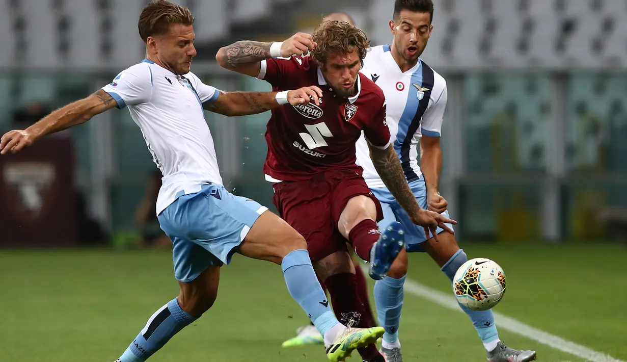 Penyerang Lazio, Ciro Immobile, berebut bola dengan pemain Torino pada laga lanjutan Serie A pekan ke-29 di Stadion Olimpico Grande Torino, Rabu (1/7/2020) dini hari WIB. Lazio menang 2-1 atas Torino. (AFP/Isabella Bonotto)