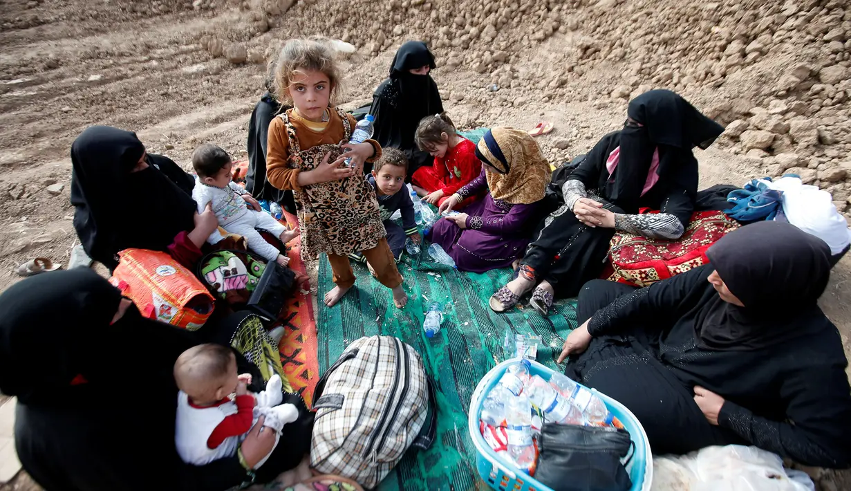 Sejumlah perempuan dan anak-anak Irak duduk di dekat tanggul setelah melarikan diri dari desa dikuasai ISIS, Irak, Senin (31/10). (REUTERS / Azad Lashkari )