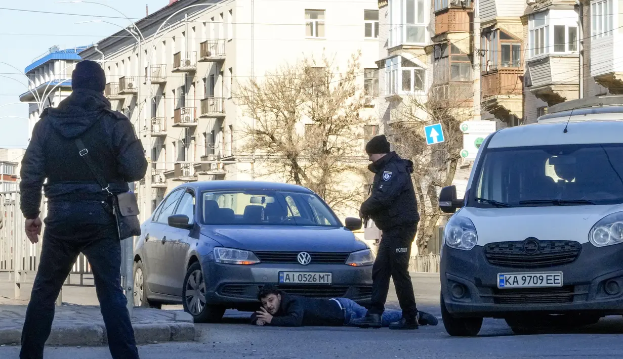 Polisi Ukraina menahan seorang pengemudi mobil di sebuah jalan di Kyiv, Ukraina, Sabtu (26/2/2022). Pasukan Rusia menyerbu ke arah ibu kota Ukraina pada Sabtu (26/2), dan pertempuran jalanan pecah saat pejabat kota mendesak penduduk untuk berlindung. (AP Photo/Efrem Lukatsky)