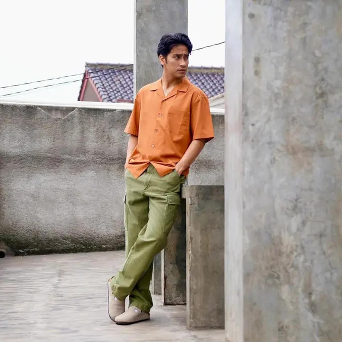 Abidzar menampilkan paduan warna yang serasi dengan mengenakan kemeja oranye dan cargo pants hijau army.