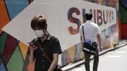 Seorang pria yang mengenakan masker berjalan di jalan belakang di distrik Shibuya, Tokyo, Kamis (30/9/2021). Jepang akan mencabut keadaan darurat COVID-19 di semua wilayah pada akhir September. (AP Photo/Eugene Hoshiko)