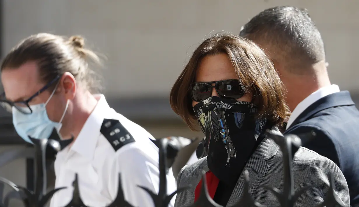 Aktor Johnny Depp memakai kacamata hitam dan syal saat menghadiri sidang pencemaran nama baik di Pengadilan Tinggi, London, Inggris, Selasa (21/7/2020). Johnny Depp menggugat tabloid The Sun atas artikel yang menyebut dirinya telah melakukan kekerasan terhadap sang istri. (AP Photo/Alastair Grant)