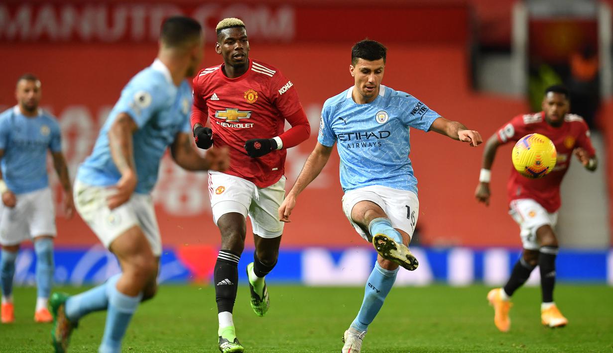 Gelandang Manchester City, Rodri (kanan), melepaskan umpan dalam laga lanjutan Liga Inggris 2020/21 pekan ke-12 melawan Manchester United di Old Trafford Stadium, Sabtu (12/12/2020). Manchester City bermain imbang 0-0 dengan Manchester United. (AFP/Paul Ellis/Pool)