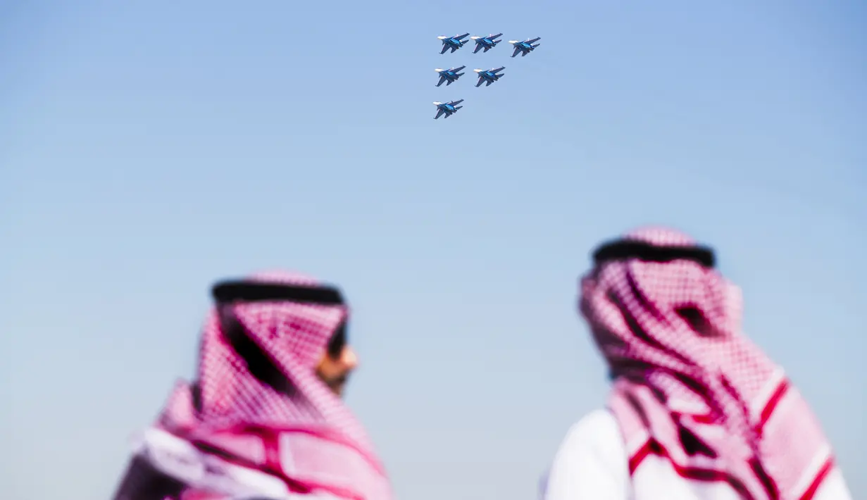 Pria Arab menyaksikan Ksatria Rusia melakukan aksi di Dubai Air Show di Dubai, Uni Emirat Arab (14/11/2021). Dubai Air Show dua tahunan dibuka Minggu ketika penerbangan komersial mencoba untuk melepaskan diri dari pandemi virus corona. (AP Photo/Jon Gambrell)