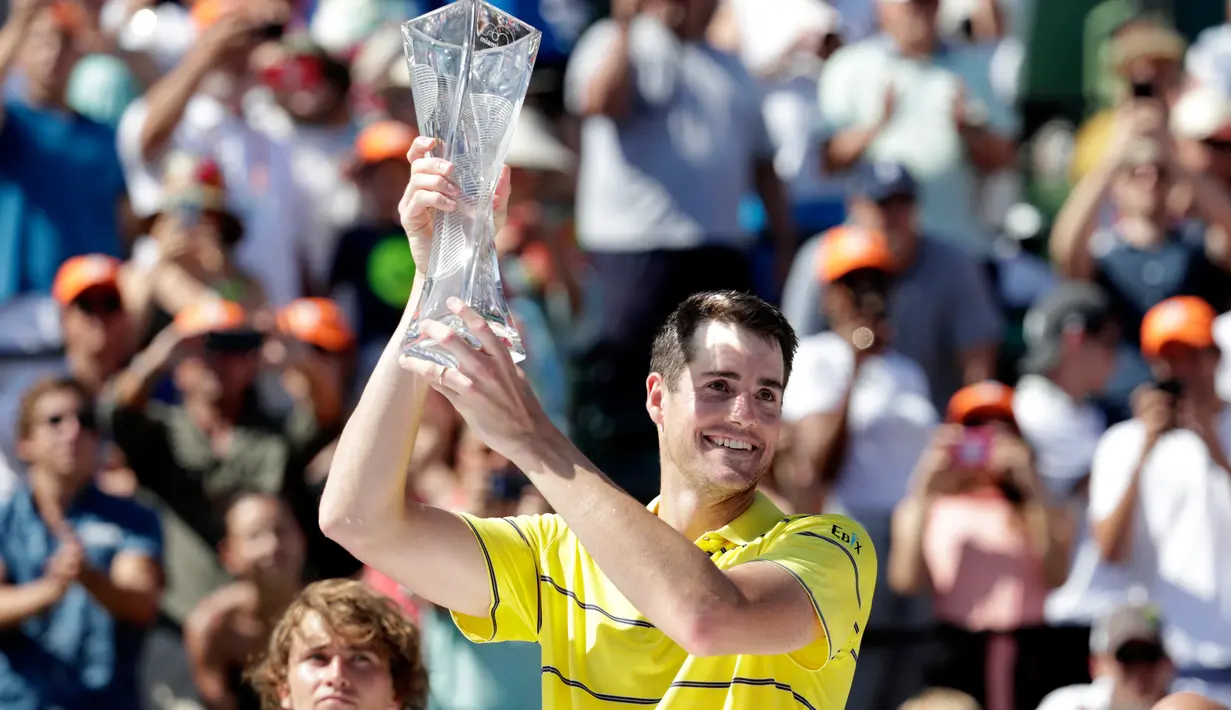 Petenis AS, John Isner memegang trofi seusai meraih gelar juara Miami Terbuka 2018 di Key Biscayne, Minggu (1/4). Pada laga final yang menegangkan tersebut, Isner sukses menaklukkan petenis Jerman Alexander Zverev 6-7, 6-4, 6-4. (AP/Lynne Sladky)