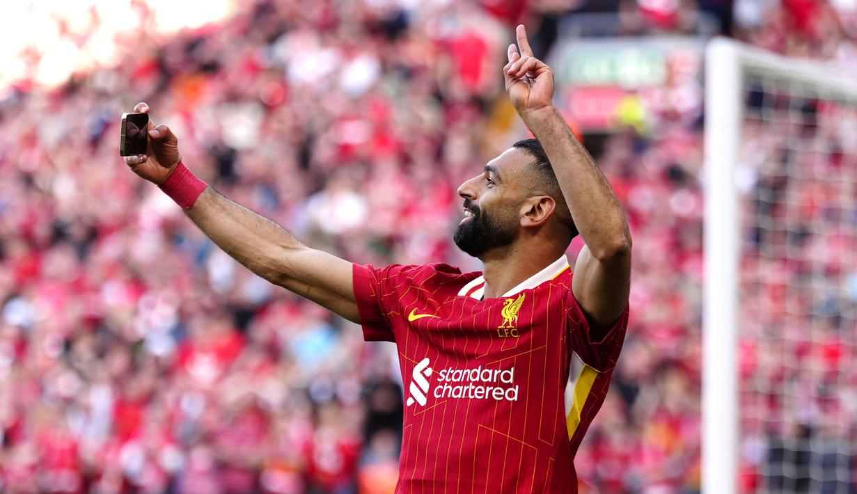 Pemain Liverpool, Mohamed Salah merayakan golnya dengan berswafoto bersama para pendukung timnya dalam laga lanjutan Liga Inggris 2024/2025 melawan Tottenham Hotspur di Anfiled, Liverpool, Inggris, Minggu (27/04/2025) waktu setempat. (AP Photo/PA/Peter Byrne)