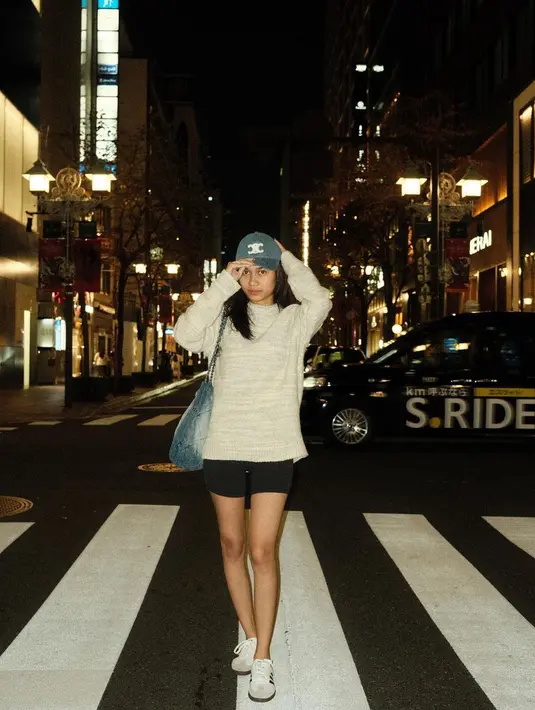 Gaya yang terlihat sederhana lainnya dari Azizah Salsha. Ia berjalan-jalan di malam hari mengenakan sweater abu-abu, dipadu celana pendek berwarna hitam. Ia memadukan gayanya dengan denim bag dari Chanel dan topi denim dari Celine, serta sneakers putih.  [Foto: Instagram/azizahsalsha_]