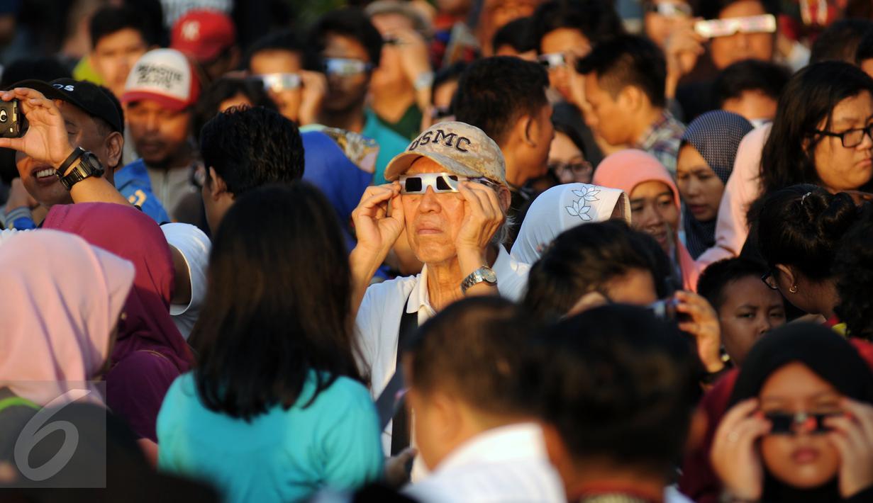 Warga menggunakan kacamata khusus untuk melihat proses gerhana matahari di sekitar Taman Ismail Marzuki, Jakarta, Rabu (9/3/2016). Di Jakarta, fenomena gerhana matahari 90% bisa diamati selama 2,11 menit. (Liputan6.com/Helmi Fithriansyah)   