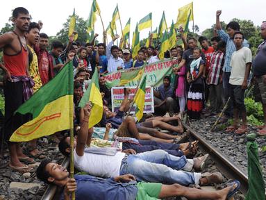 Ratusan pengunjuk rasa dari Front Rakyat Pribumi Tripura (IPFT) melakukan pemblokiran jalur rel kereta api saat menggelar demo di Khamtingbari di dekat perbatasan Agartala, India, Senin (10/7). (AFP Photo/ Arindam Dey)