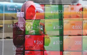 Pejalan kaki melintas dekat layar pergerakan Indeks Harga Saham Gabungan (IHSG) di kawasan Jakarta, Senin (13/1/2020). IHSG menguat 0,34 persen atau 21 poin ke level 6.296 pada penutupan perdagangan Senin (13/1) sore ini. (Liputan6.com/Angga Yuniar)