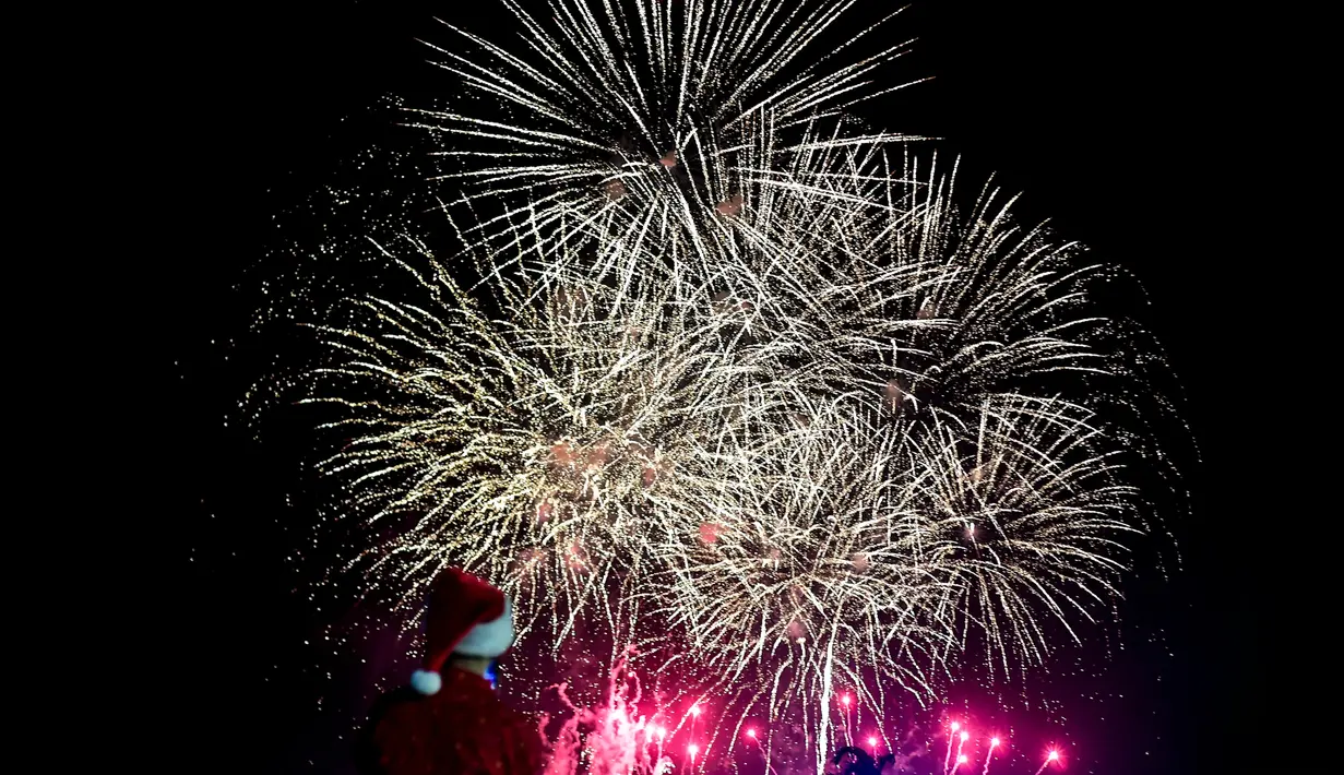 Seorang pria mengenakan kostum santa melihat kembang api selama parade Natal di Panama City (16/12). Warga Panama tengah mempersiapkan diri menyambut datangnya Natal 2018 yang jatuh pada tanggal 25 Desember. (AFP Photo/Luis Acosta)