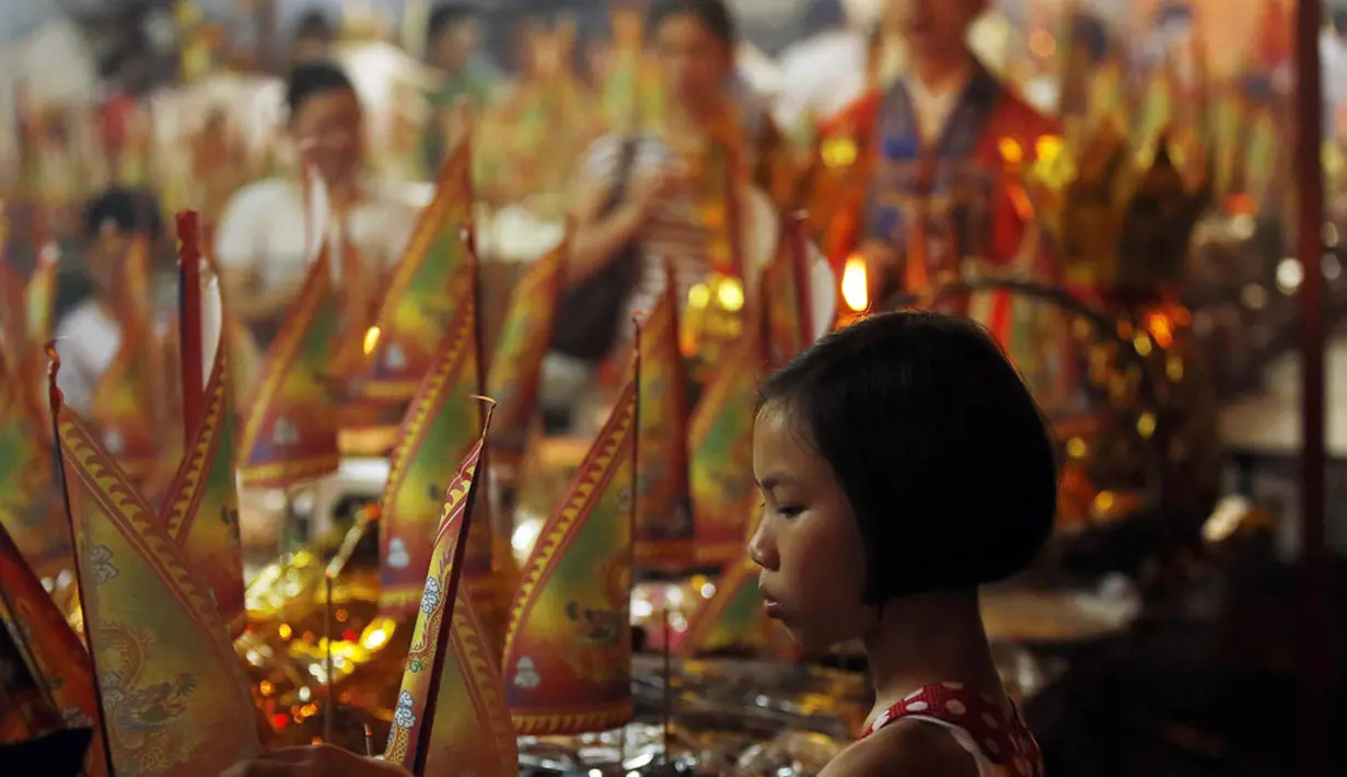 Hungry Ghost merupakan kepercayaan saat gerbang neraka terbuka untuk membiarkan roh-roh yang berkeliaran di negeri orang hidup mencari makanan. Seorang anak menghiasi persembahan di festival Hungry Ghost, Kuala Lumpur, (3/8/2014). (REUTERS/Olivia Harris)