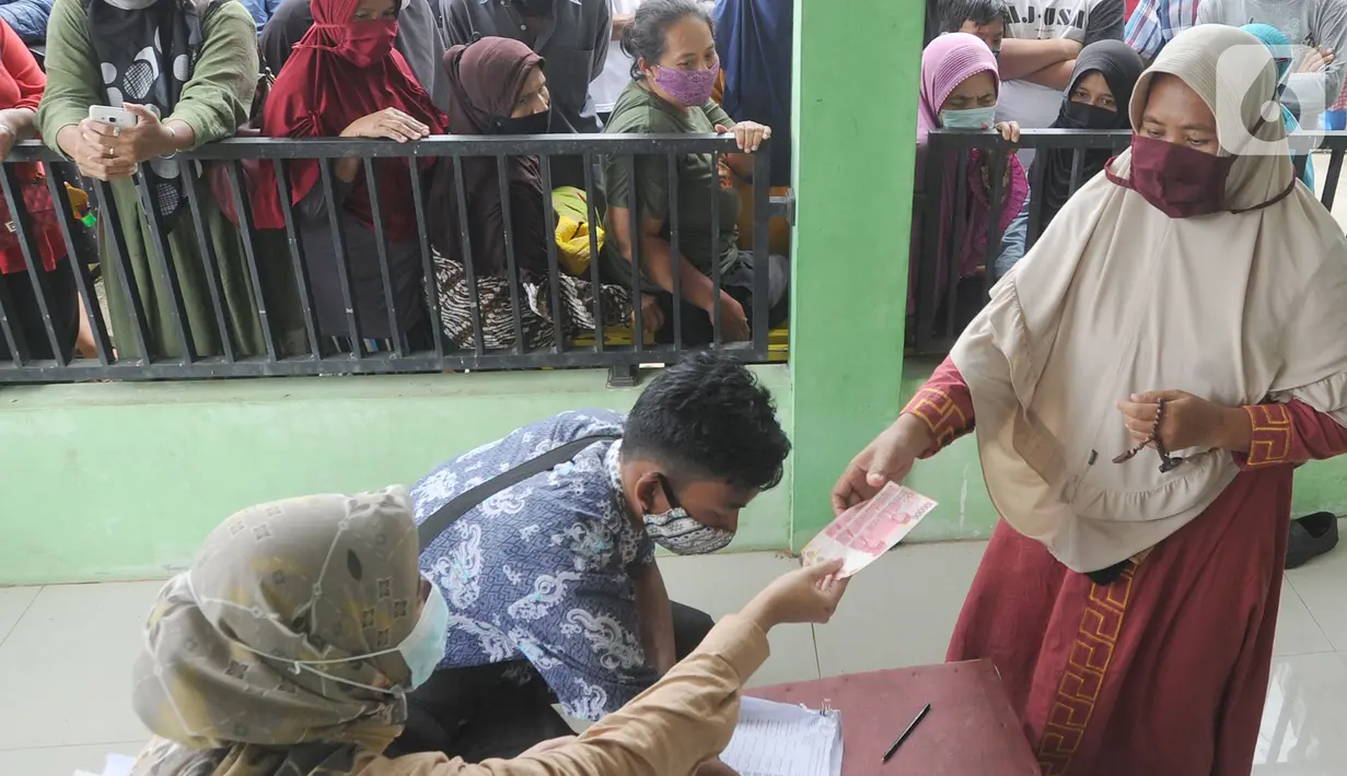 Warga menerima uang Bantuan Sosial Tunai (BST) bulan Januari di halaman Masjid Jami Al-Hidayah RW 01 Bedahan, Depok, Selasa (16/2/2021). Sekitar 159.470 Keluarga Penerima Manfaat (KPM) di Kota Depok menerima BST yang disalurkan PT Pos Indonesia pada Februari ini. (merdeka.com/Arie Basuki)