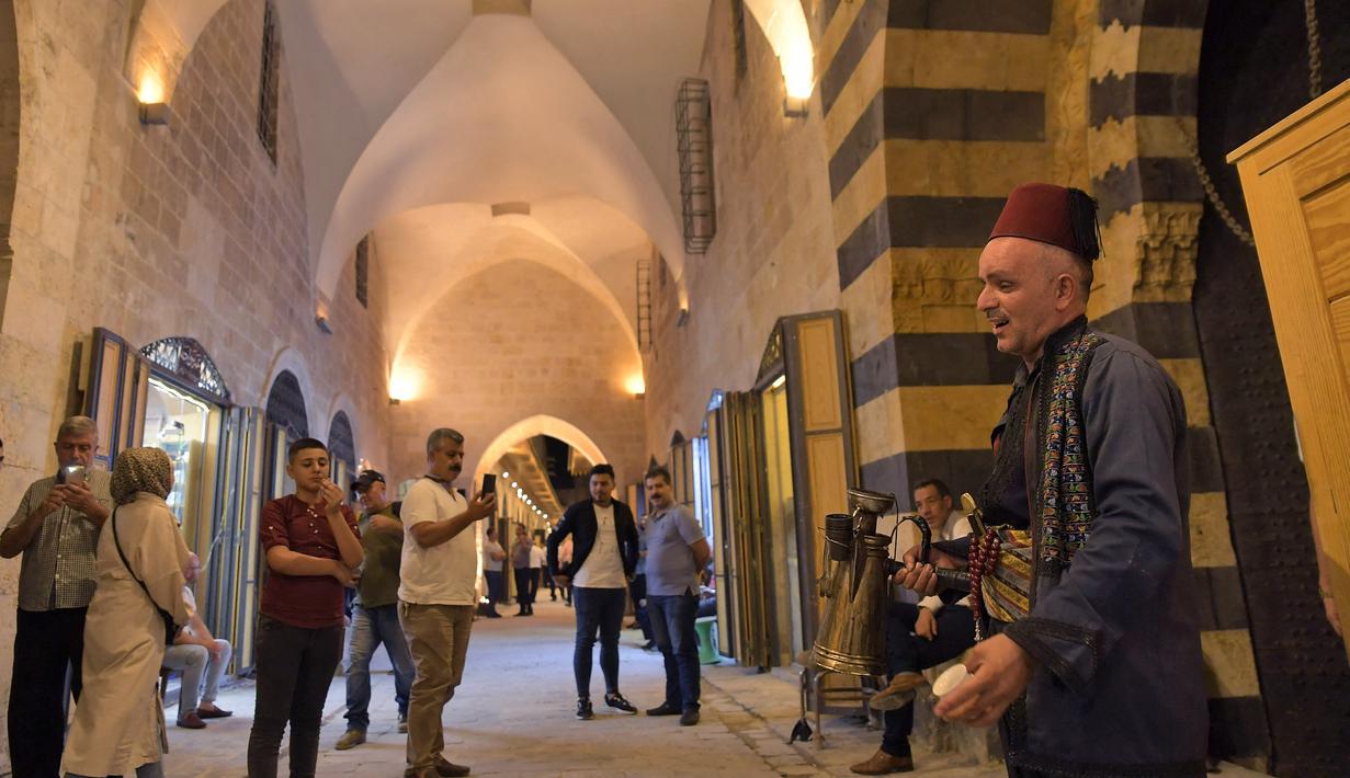 Orang-orang berjalan-jalan di "Souq Khan al-Harir" (pasar tertutup sutra) yang dibuka kembali setelah konflik bertahun-tahun di kota utara Aleppo, Suriah (29/8/2021). (AFP Photo)