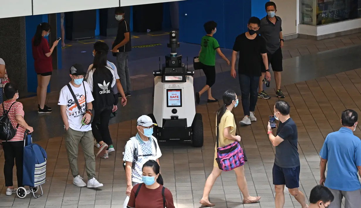 Sebuah robot berpatroli di distrik perbelanjaan dan perumahan selama uji coba oleh Home Team Science and Technology Agency (HTX)  di Singapura, Senin (6/9/2021).  Ini adalah pertama kalinya robot anonim diuji di area publik yang sibuk. (ROSLAN RAHMAN/AFP)