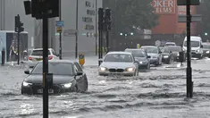 Mobil melintasi jalan yang banjir saat hujan lebat di distrik The Nine Elms London (25/7/2021). Banjir parah terjadi di Ibu Kota Inggris London yang menyebabkan lumpuhnya sejumlah area di kota tersebut. (AFP/Justin Tallis)